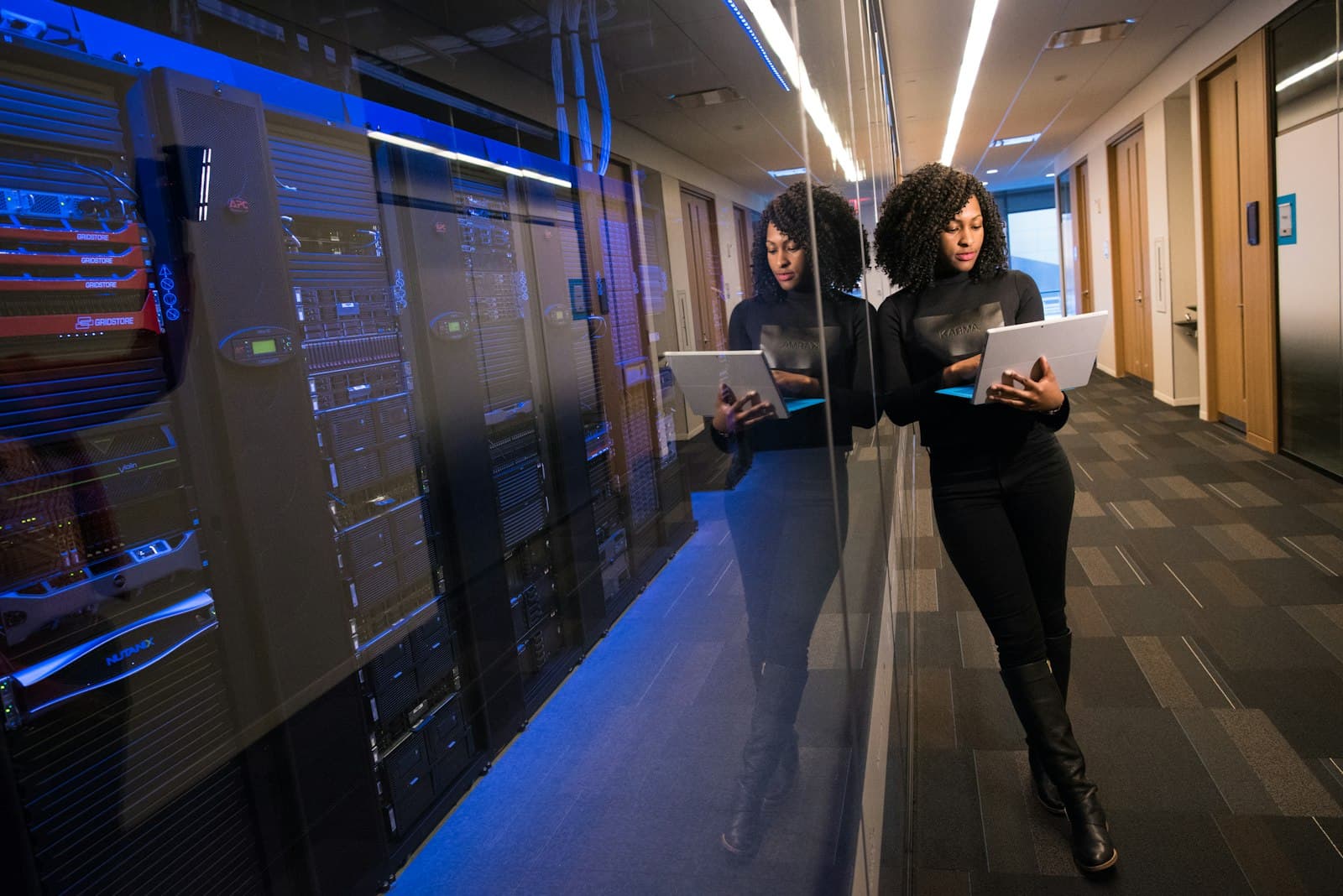 An engineer holding a laptop beside server racks in a data centre